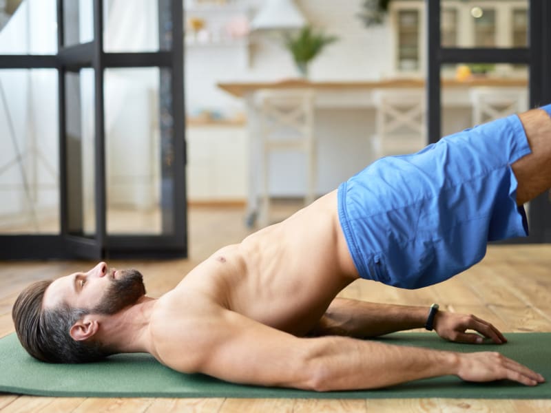 Young, fit man doing back stretches on a yoga mat