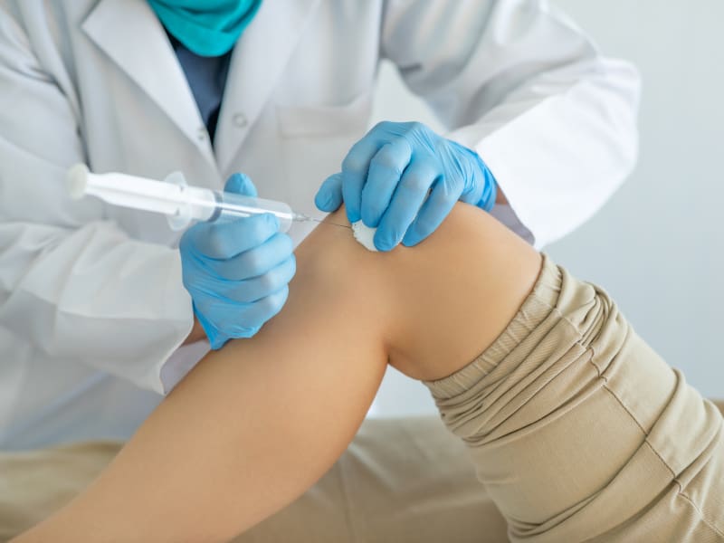 Doctor performing an injection on a woman's knee