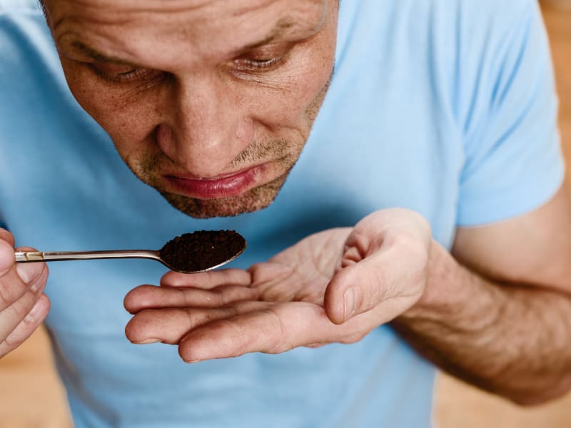 Man trying to smell a spoonful of coffee